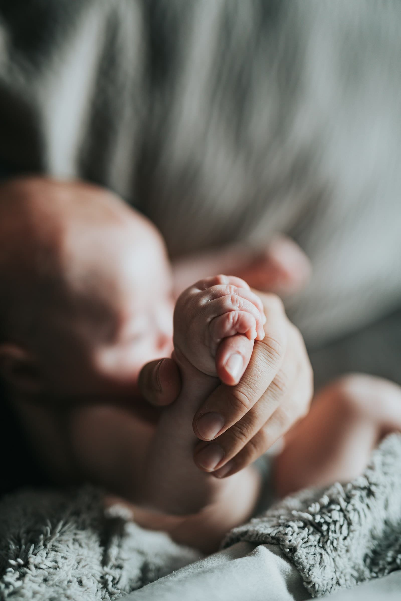 A newborn's tiny hand curled around a parent's finger
